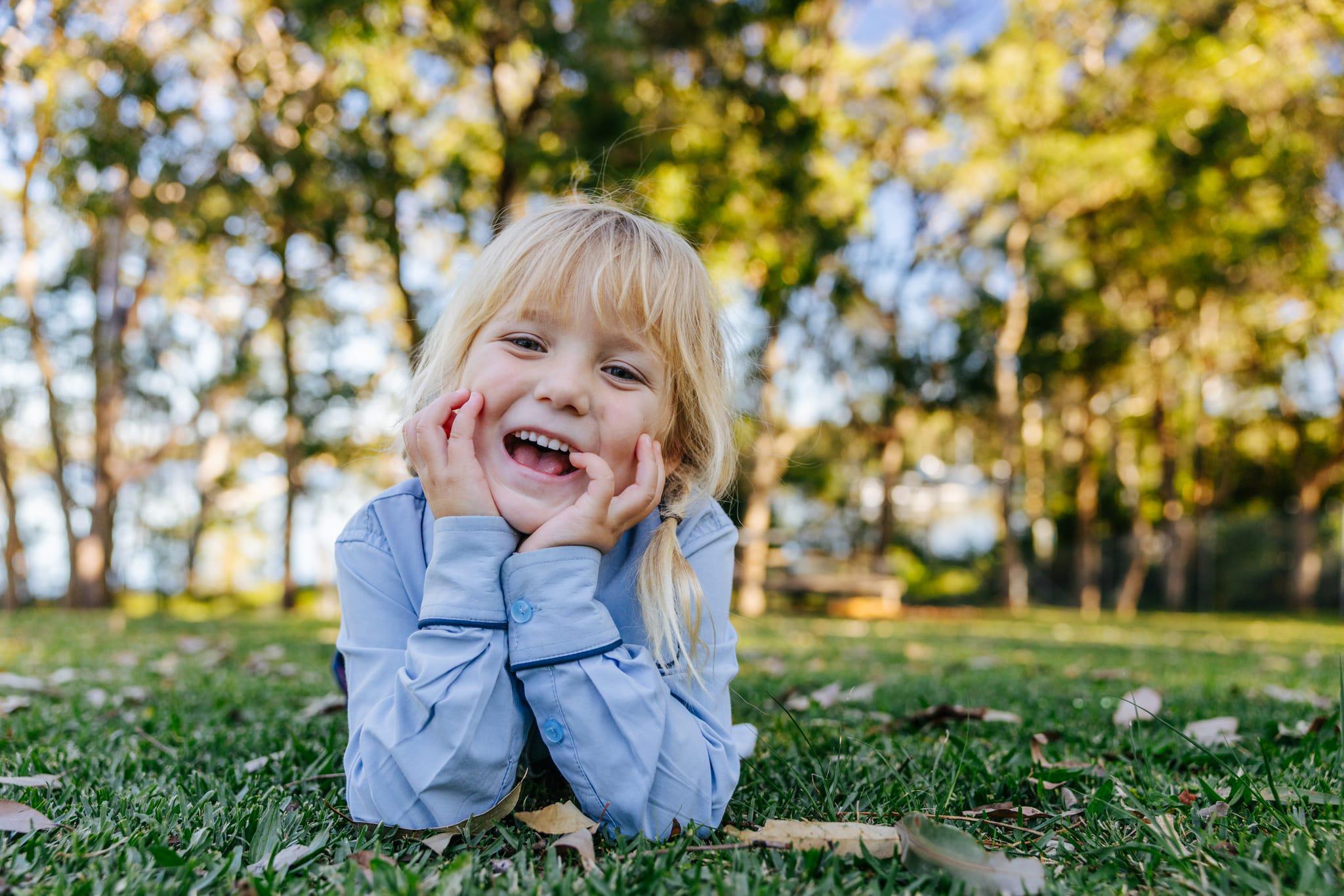 Happy young student lying on the grass under shade trees at Brightwaters Christian College near Morisset