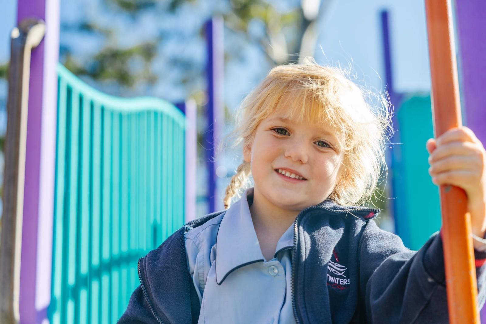 Young Pre-Kinder girl smiling on colourful playground climbing equipment