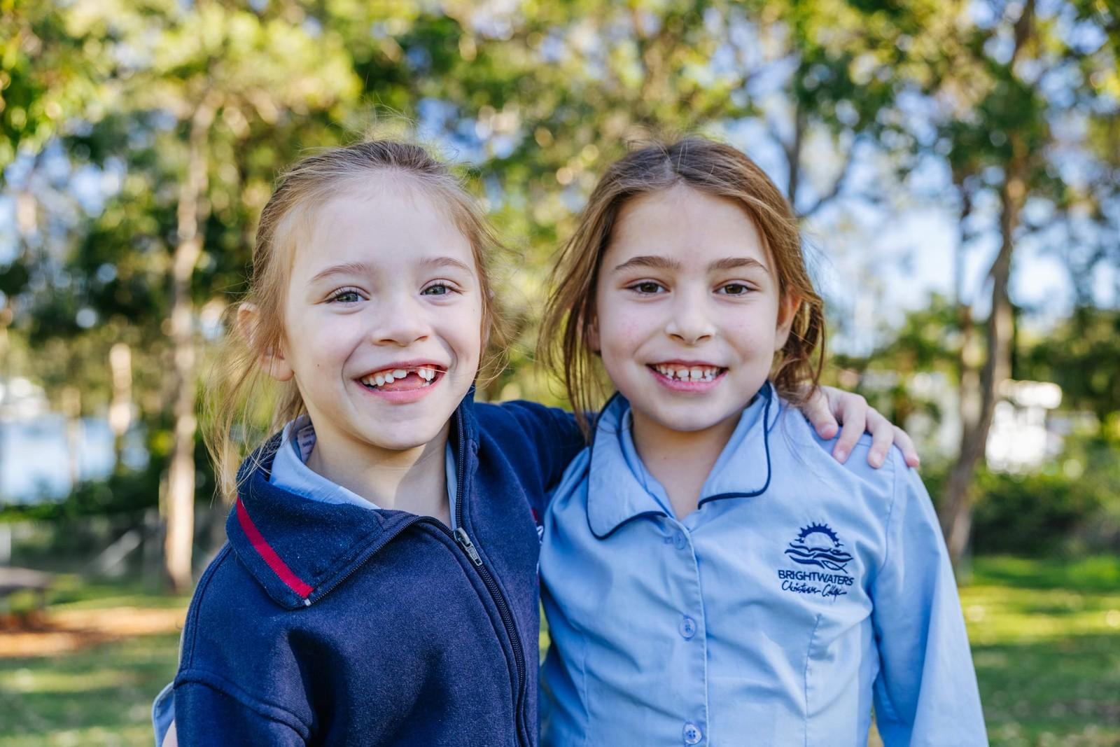 Two young students sharing a smile together on the school grounds