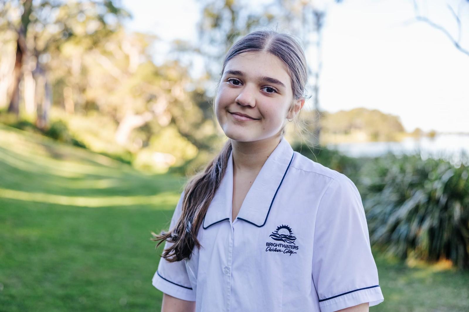 Secondary student smiling outdoors on the lakeside school grounds at Lake Macquarie