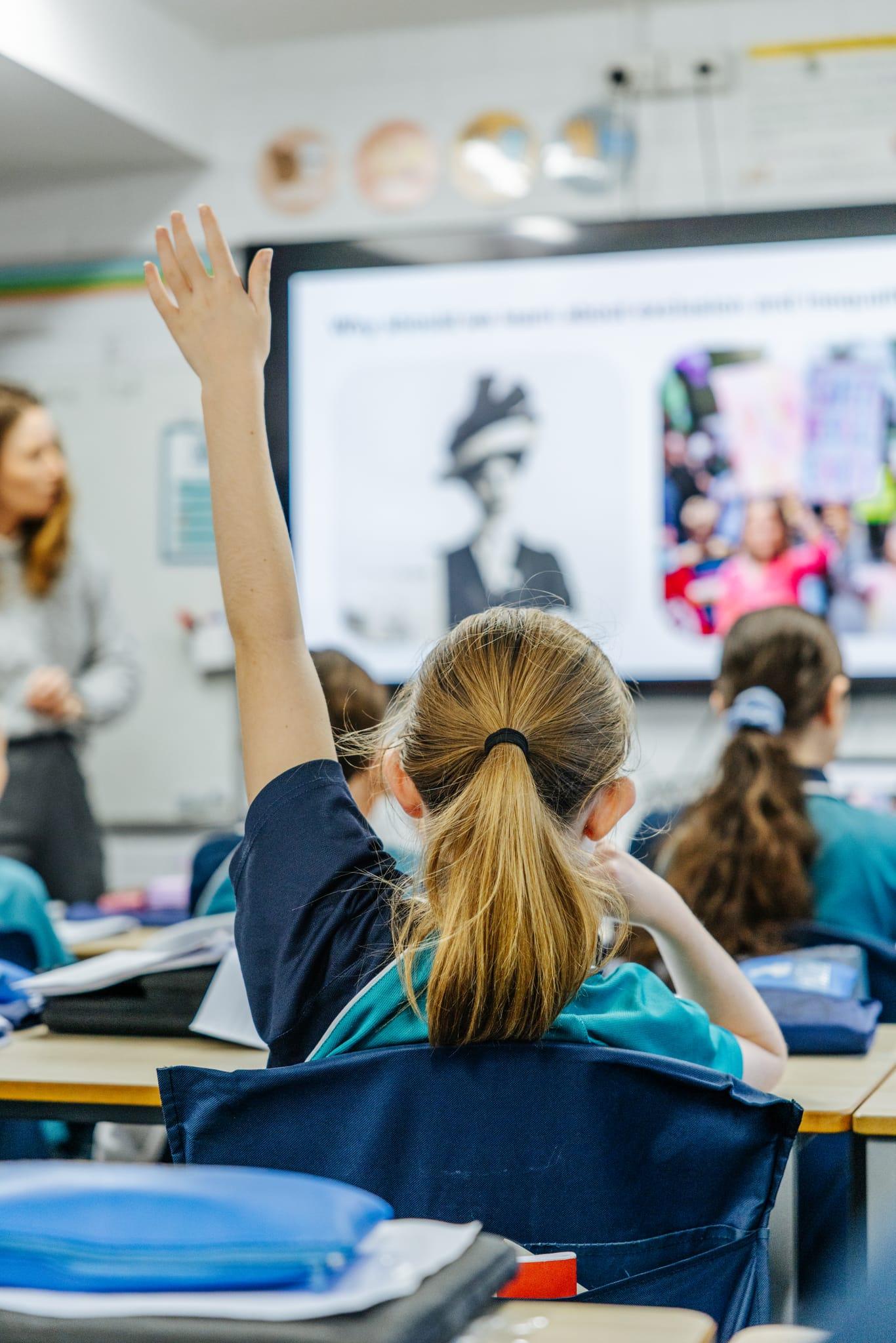 Student raising a hand during a classroom lesson at Brightwaters CC near Morisset NSW