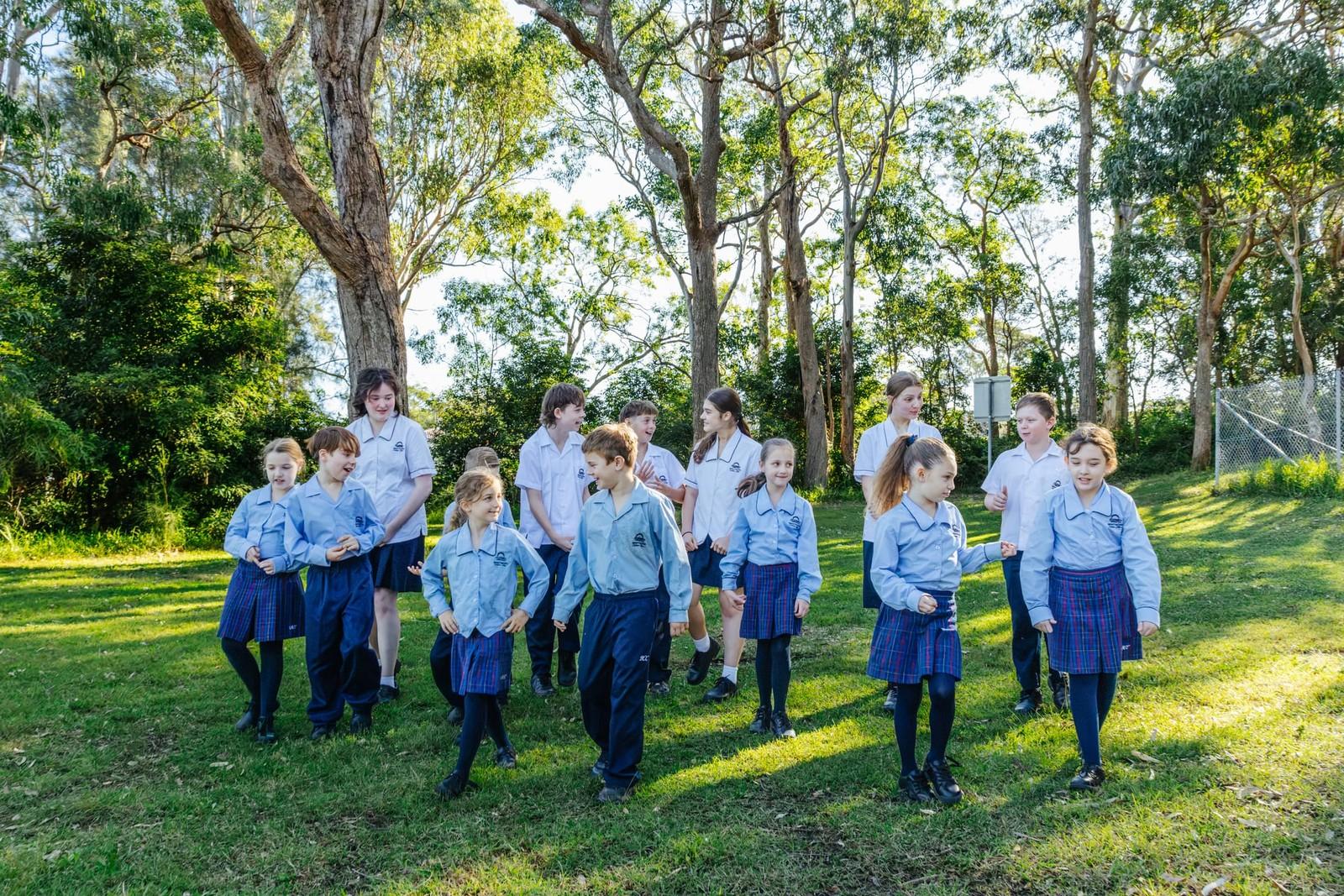 K-10 students walking together on the leafy school grounds at Lake Macquarie