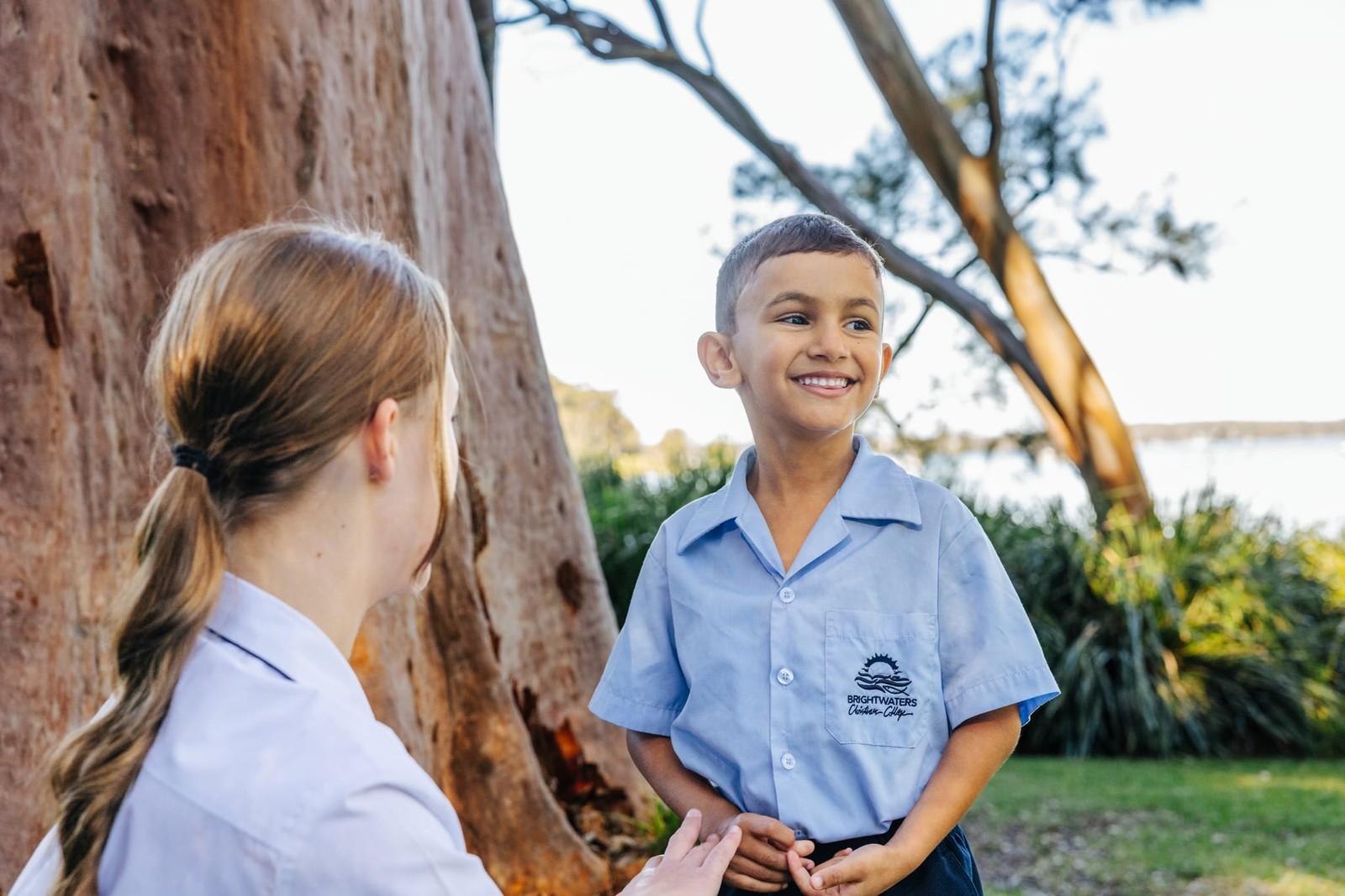Older student chatting with a young primary boy under the trees at Brightwaters Christian College