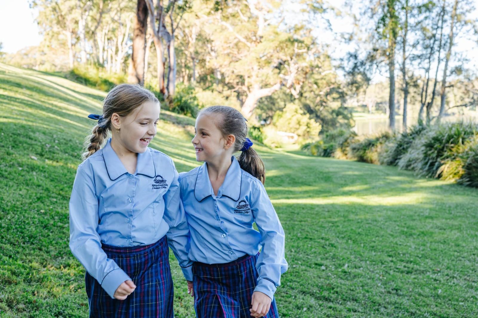 Two students walking and chatting together on the grassy school grounds near Morisset NSW