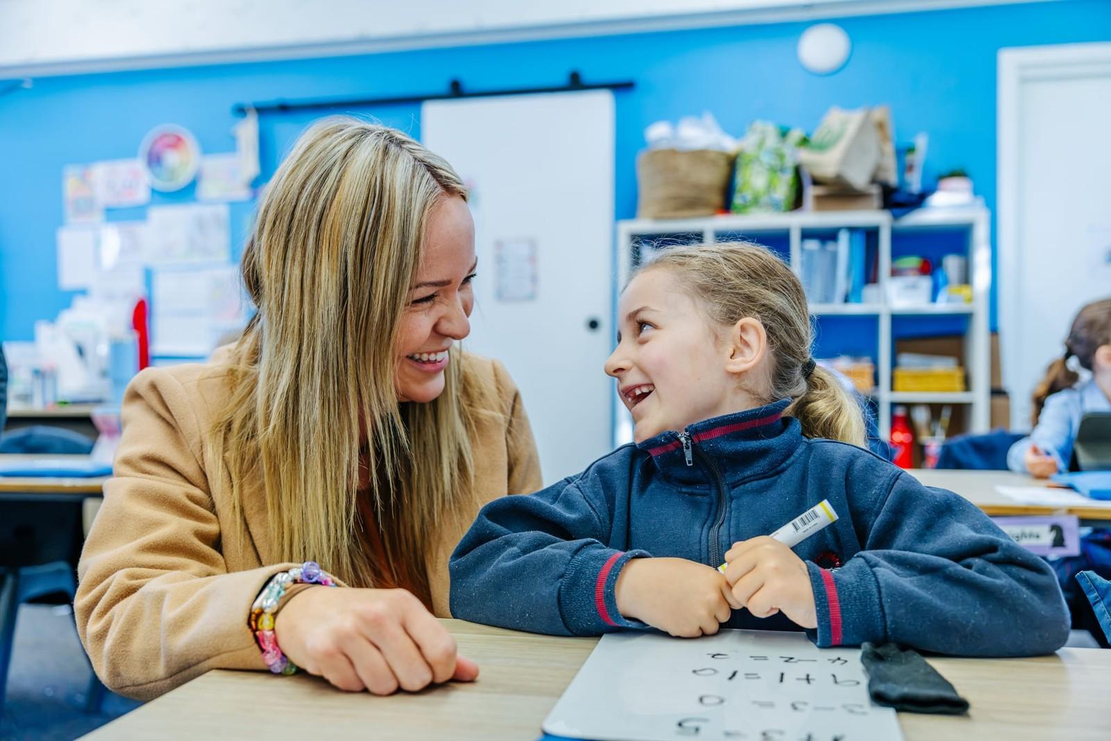 Teacher working one-on-one with a young student on a whiteboard task in a Lake Macquarie classroom.