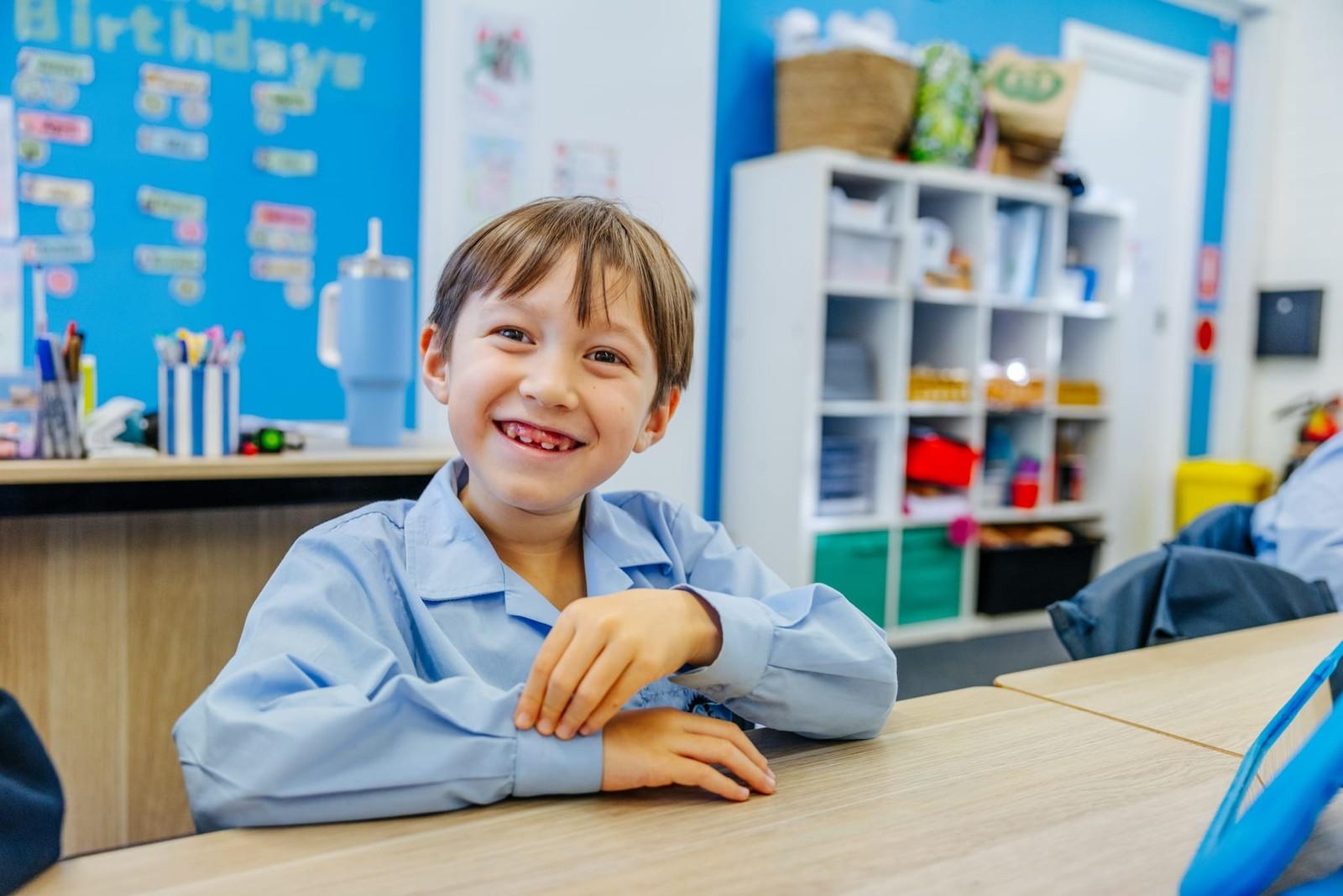 Young student smiling at a classroom desk at Brightwaters Christian College