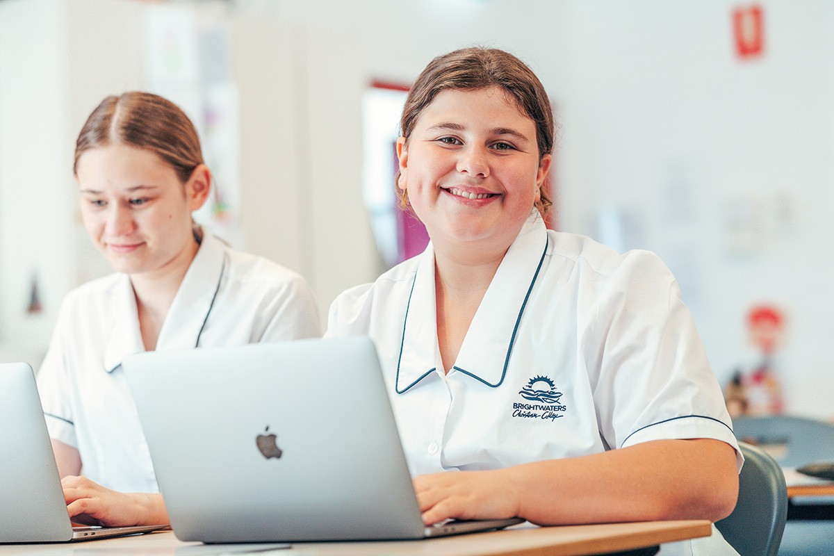 smiling year 7 student at desk with laptop