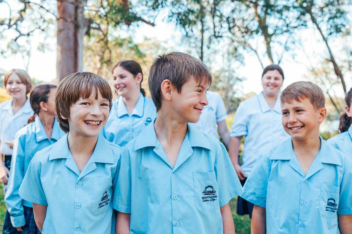 Three smiling male student friends in uniform who have built a strong relationship