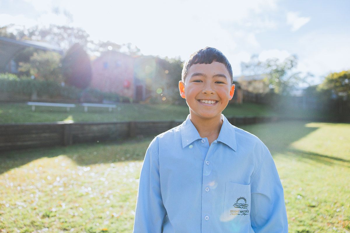 Close-up of smiling primary school student enrolled at Brightwaters Christian College with classmates in the background