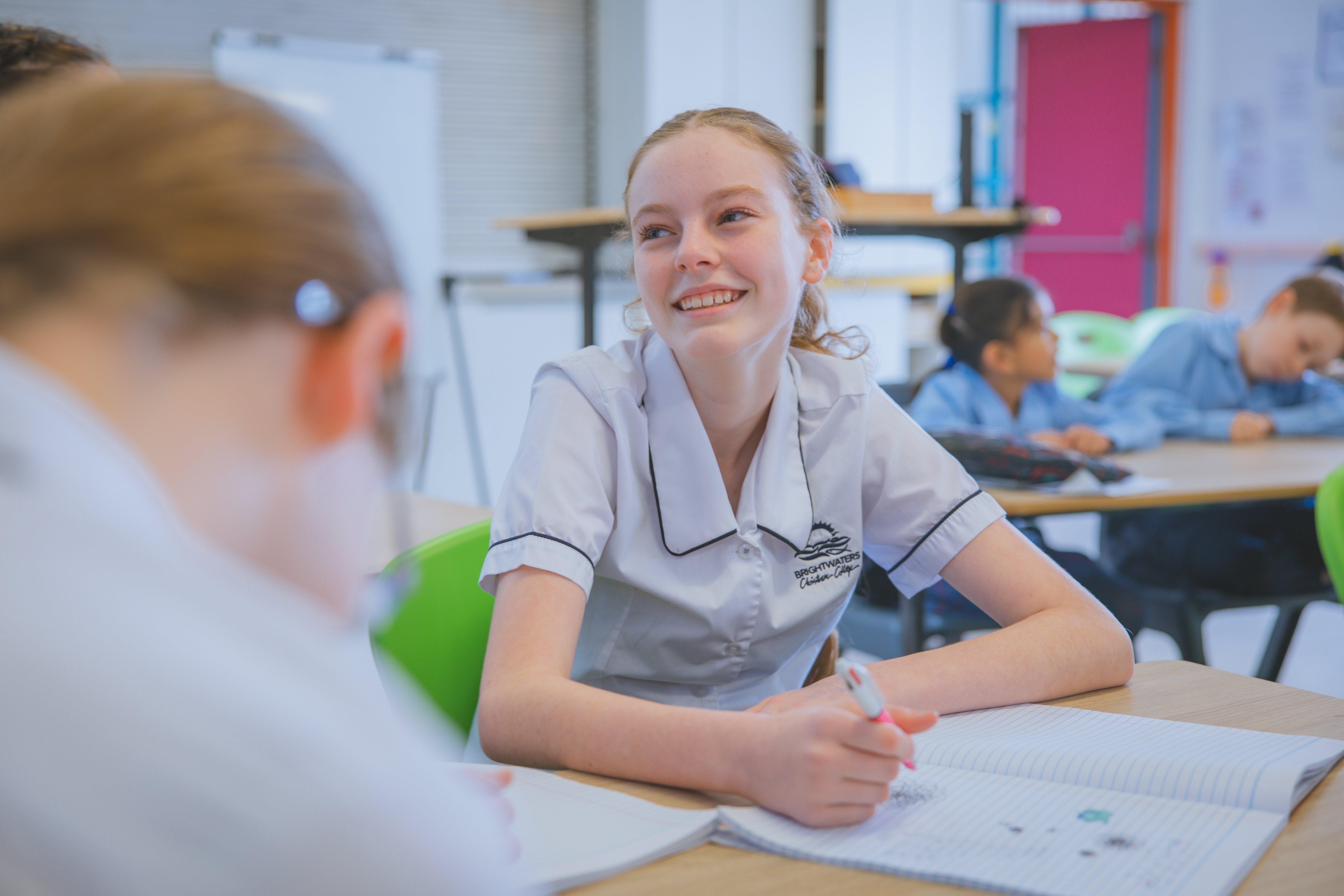 smiling year 8 student at desk with workbook at Morisset high school