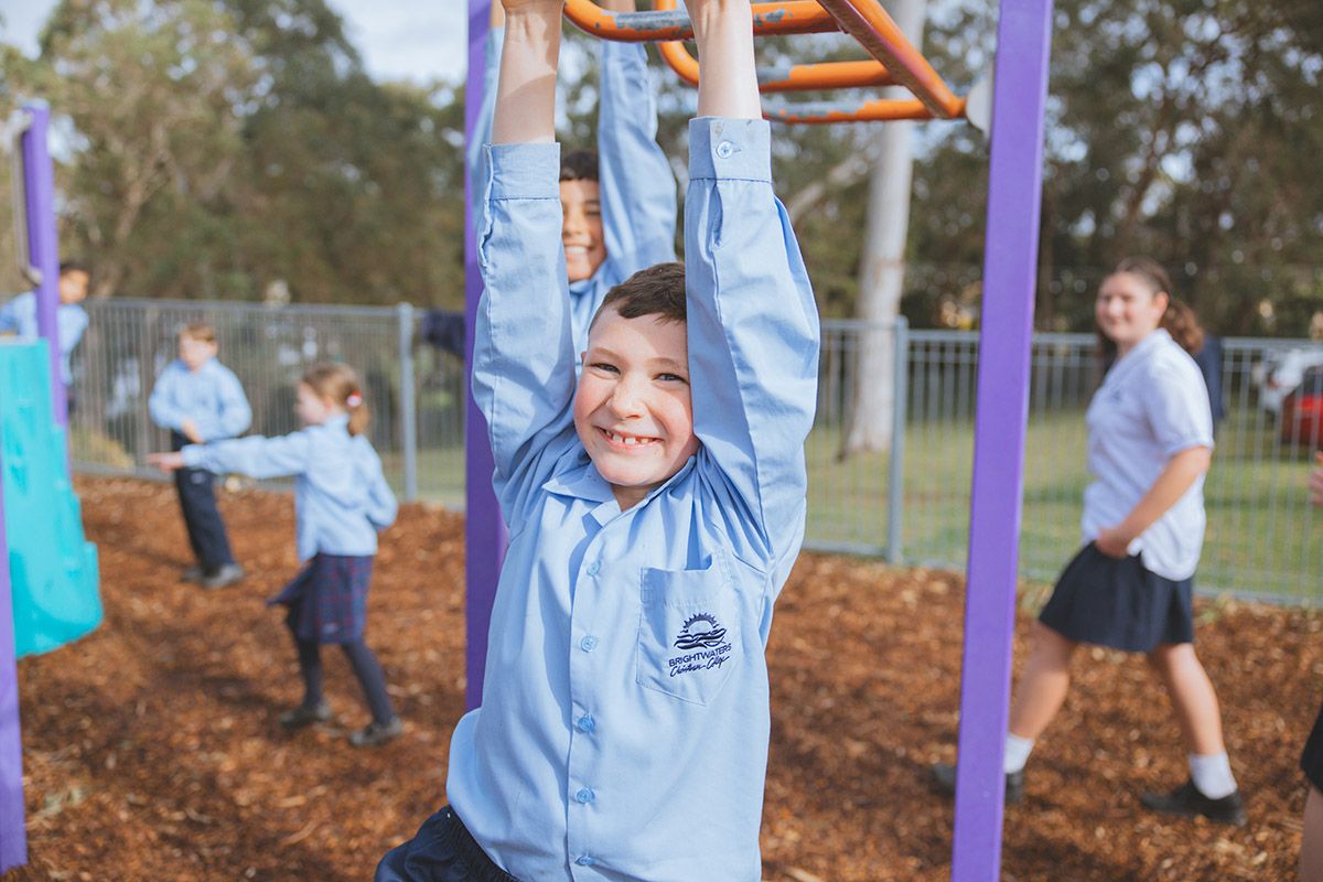 Group of girls and boys in uniform holding hands running outside on grass