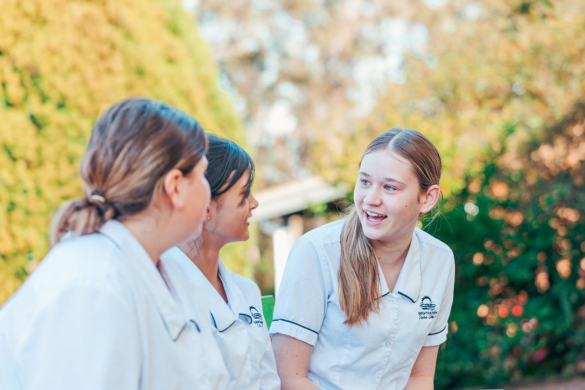 Three female high school students in conversation with one another