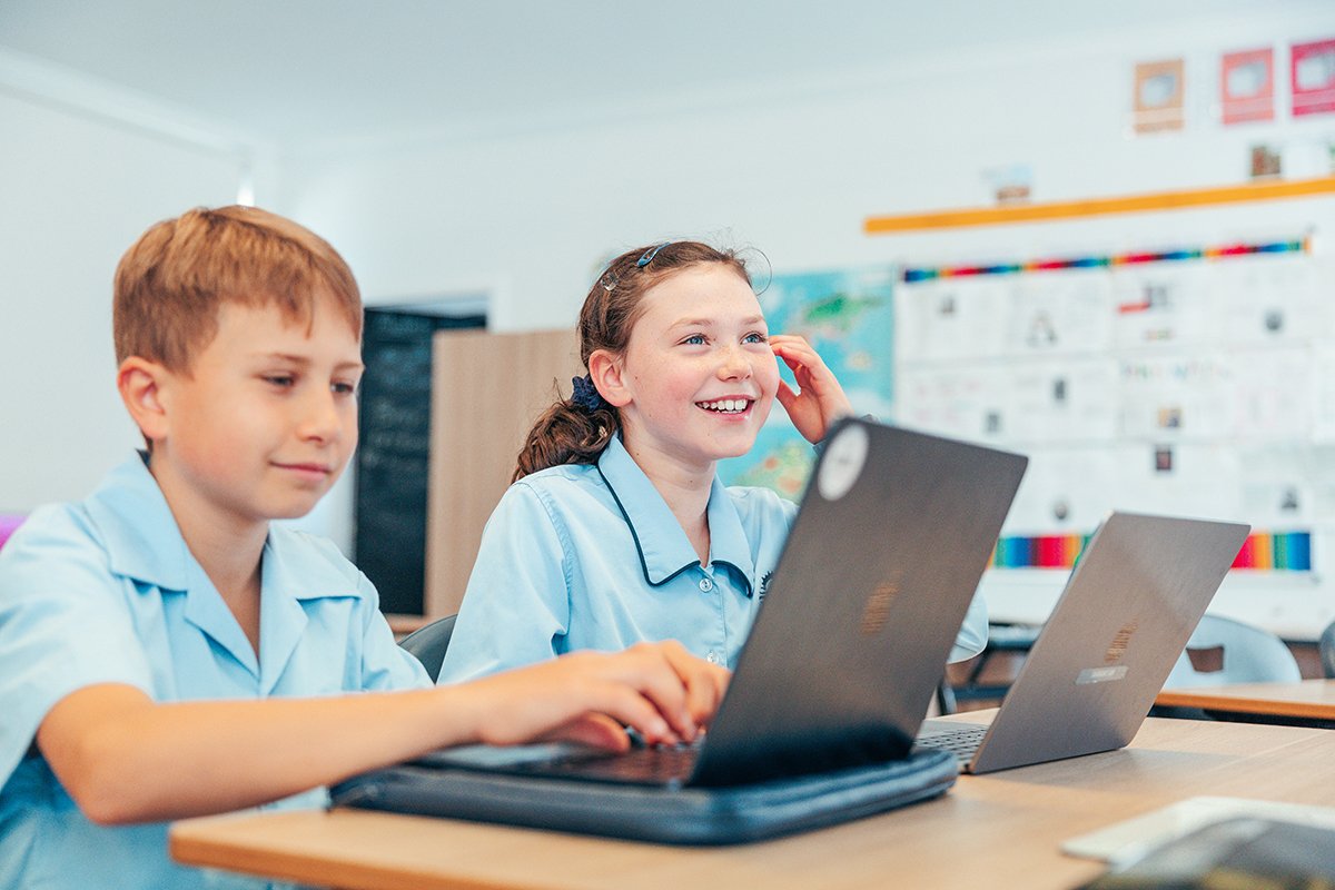 Students sitting at desk using their Macbooks